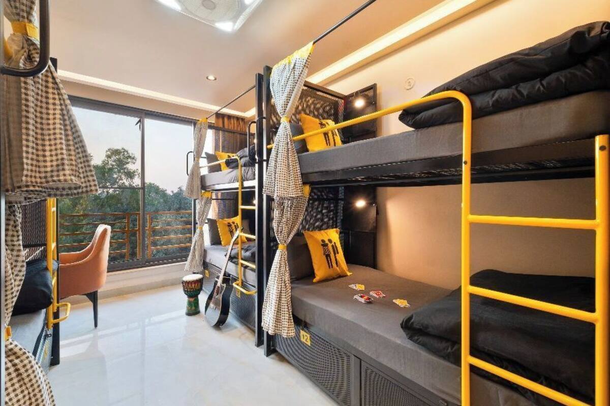 A bunk bed room with a view of the outdoors, a chair, and a small table.