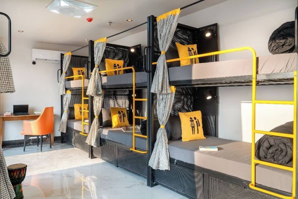 A dormitory room with bunk beds, a desk, and a chair.
