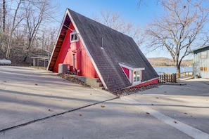 A red building with a sloped roof, a small porch, and a view of a lake. - Steps to Shared Dock: Lake of the Ozarks A-frame! (Rocky Mount)