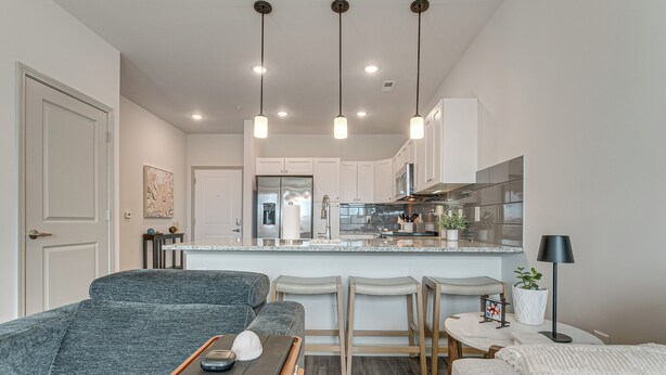 A modern kitchen with white cabinets, a central island, and pendant lighting.