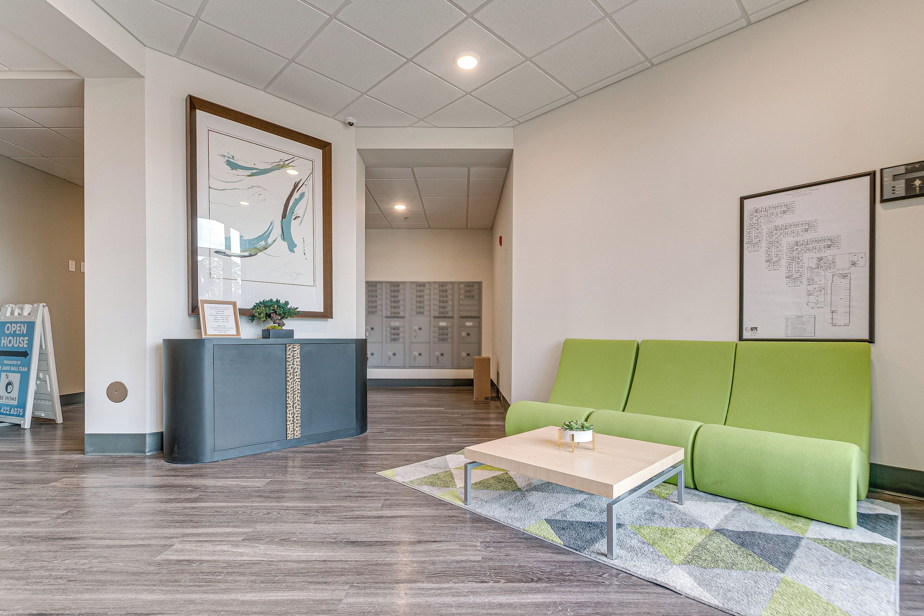 A reception area with a reception desk, a green sofa, a coffee table, and a patterned rug.