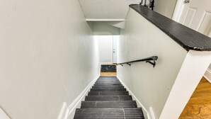 A narrow staircase with a black handrail and white walls.