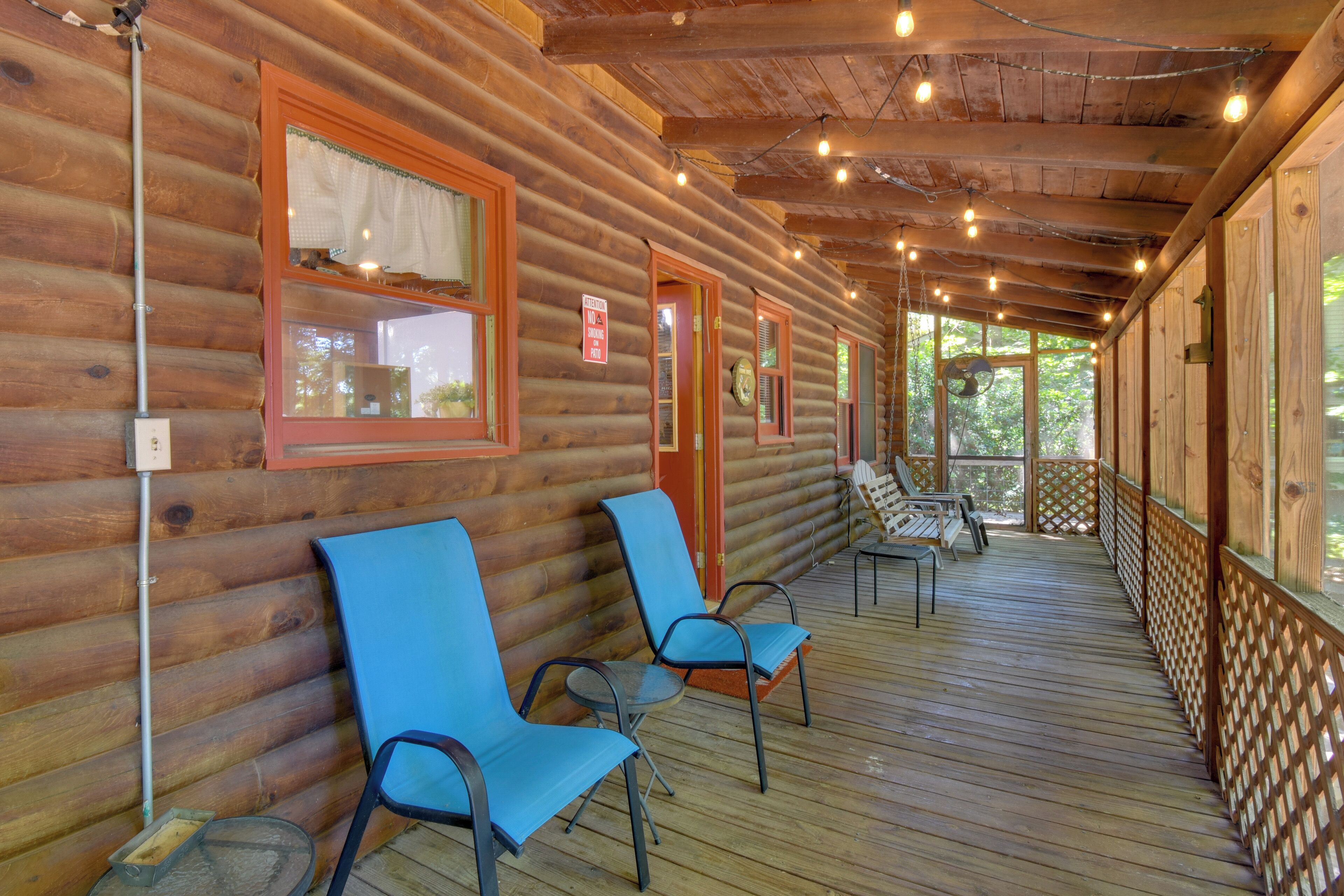 A log cabin with a porch, chairs, and a fan.