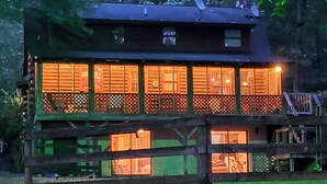 Uma cabana de madeira com várias janelas, uma varanda e uma antena parabólica no telhado.