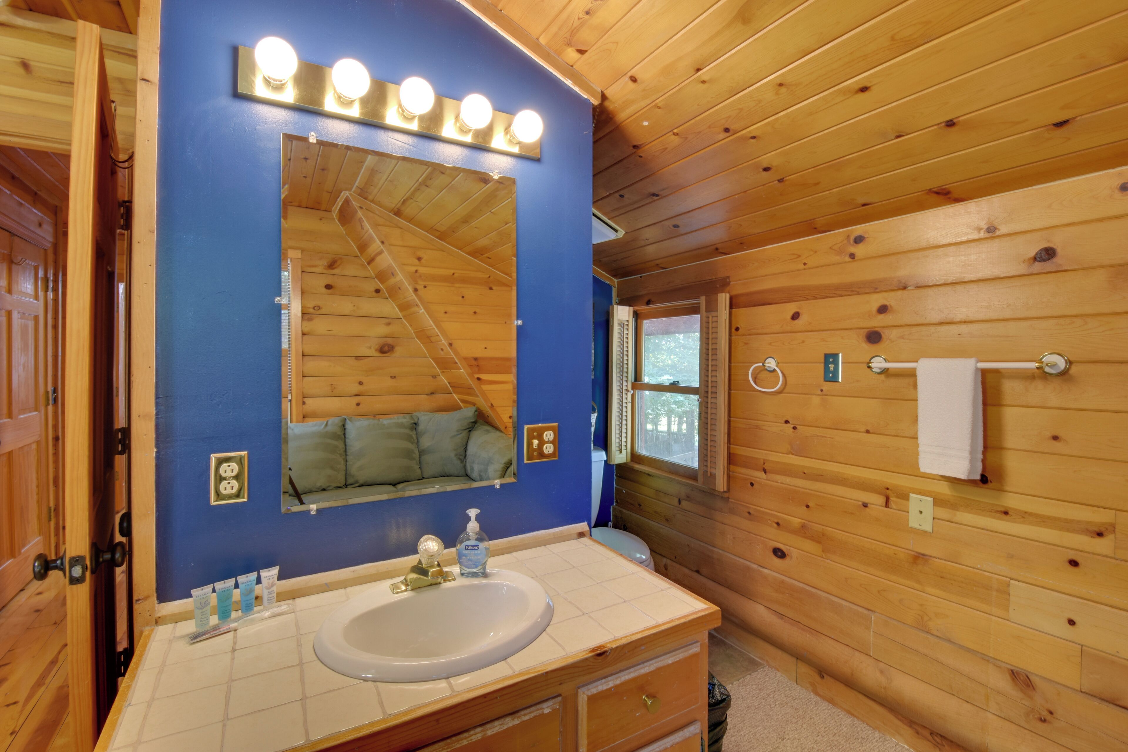 A wooden cabin bathroom with a sink, mirror, and wooden walls.