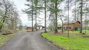 A gravel road leading to a wooden cabin surrounded by tall trees. - Willamette Valley Home on Working Horse Farm! (Scio)