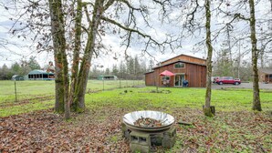 A rustic cabin with a wooden exterior, a red door, and a large window. - Willamette Valley Home on Working Horse Farm! (Scio)