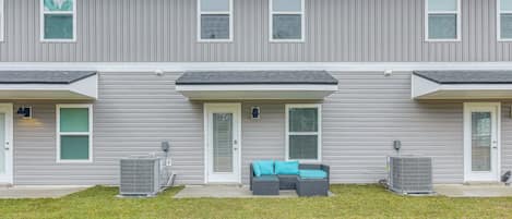 A row of townhouses with grey siding, white trim, and a front porch with outdoor seating.