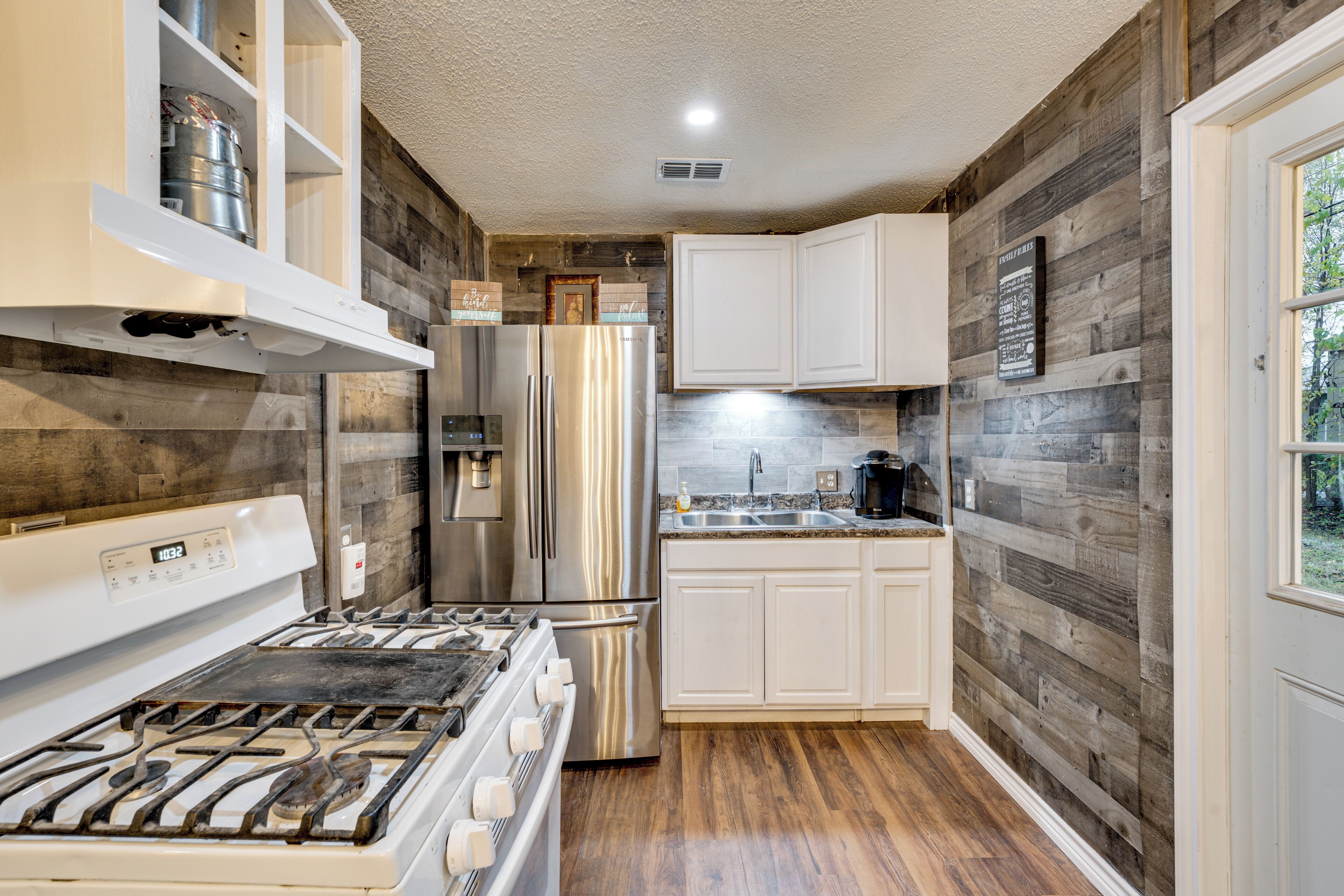 A kitchen with a stainless steel refrigerator, a stove, and white cabinets.