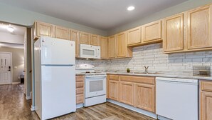 A modern kitchen with wooden cabinets, a white refrigerator, a microwave, a stove, and a dishwasher. - 2 Mi to Lenovo Center: Dog-friendly Getaway (Raleigh)