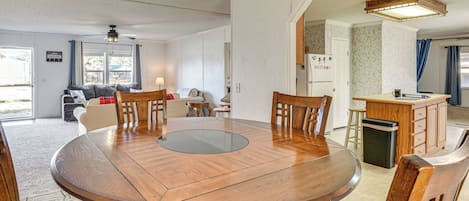 A modern kitchen with a wooden dining table, chairs, and a built-in island with a sink.