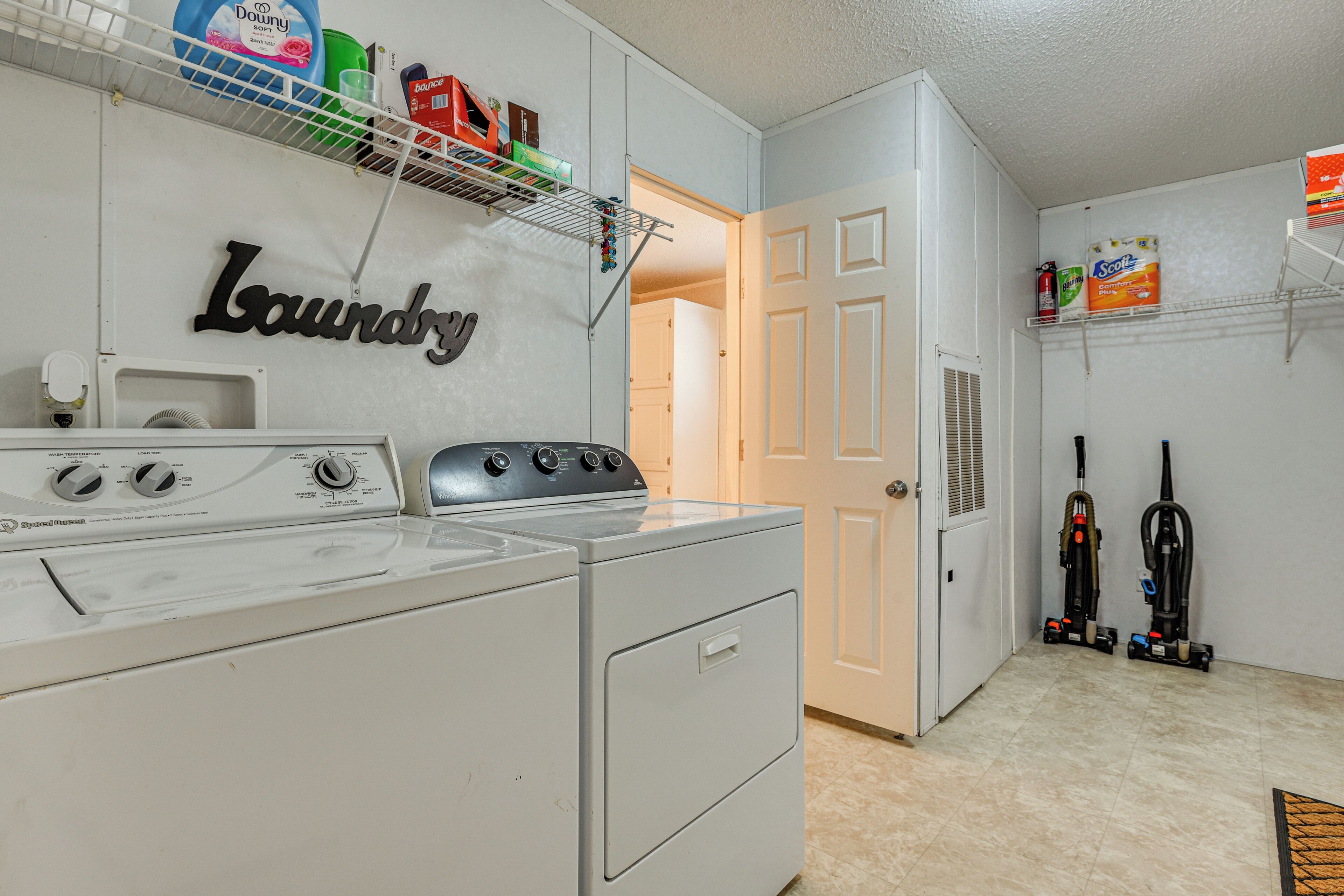 A laundry area with a washing machine, a dryer, and shelves with cleaning supplies.