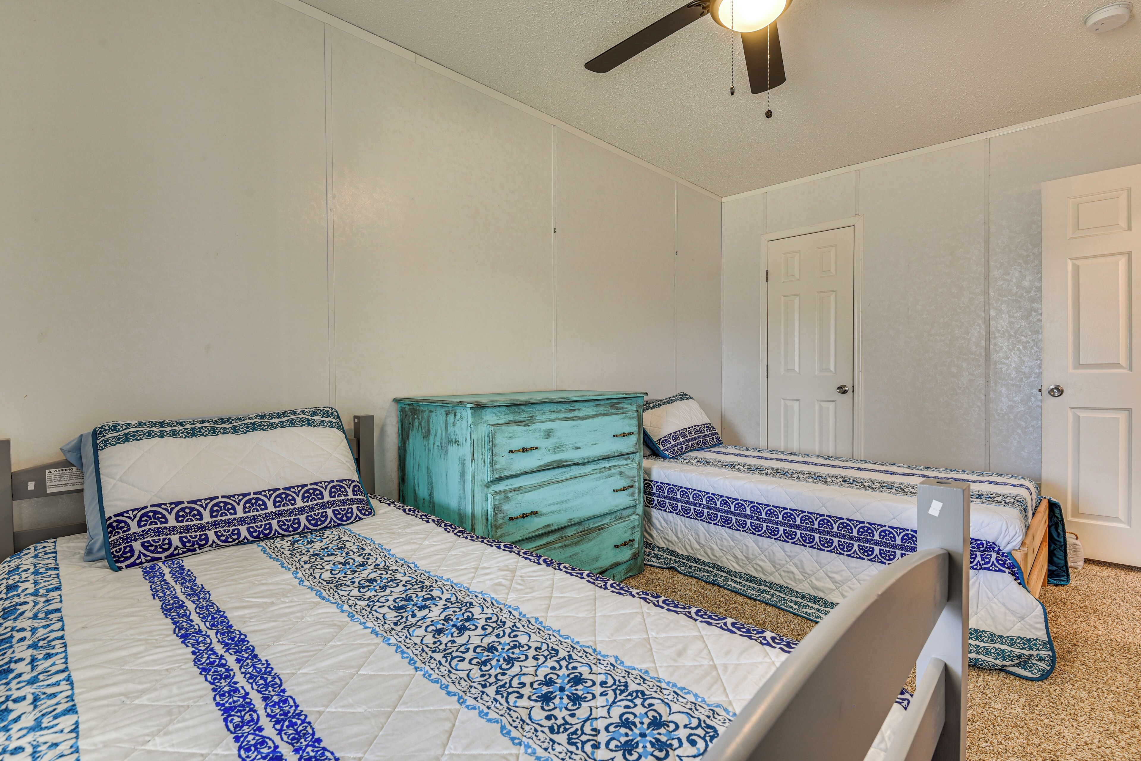 Un dormitorio con dos camas, un aparador y un ventilador de techo.