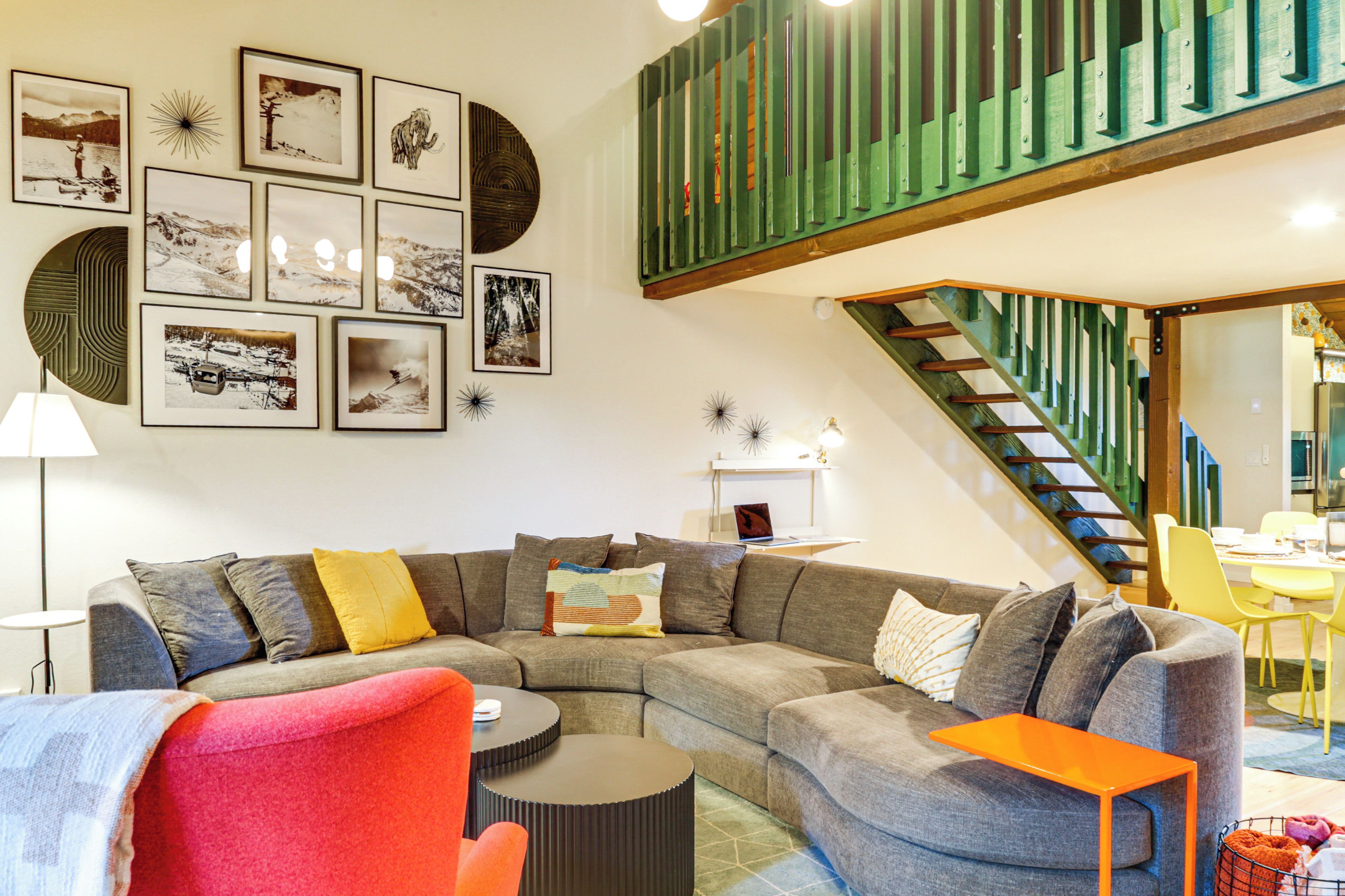 A modern living room with a sectional sofa, a round coffee table, and a vibrant orange chair.