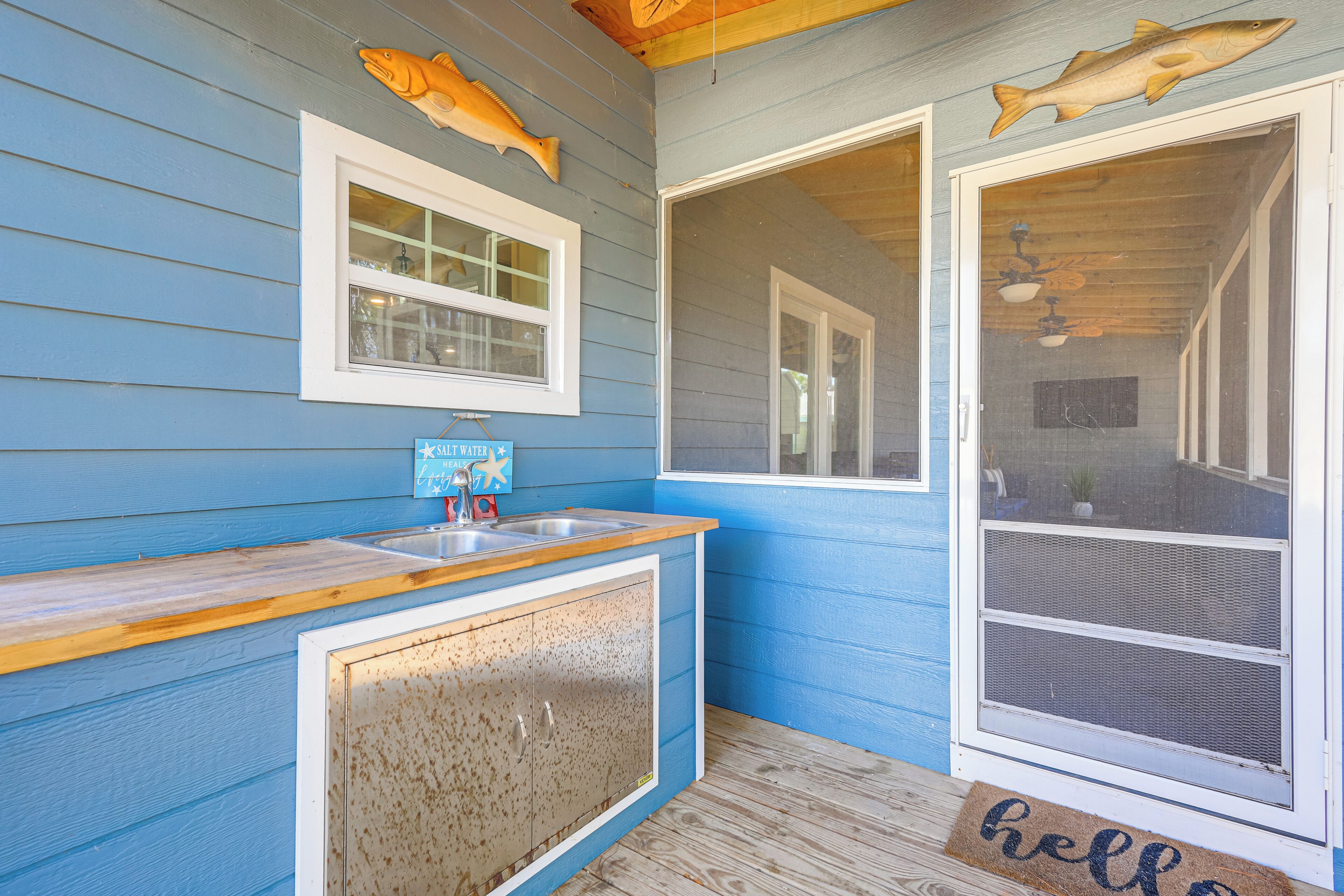 Fachada azul con mostrador de madera y puerta con un tapete que dice 'hola'.