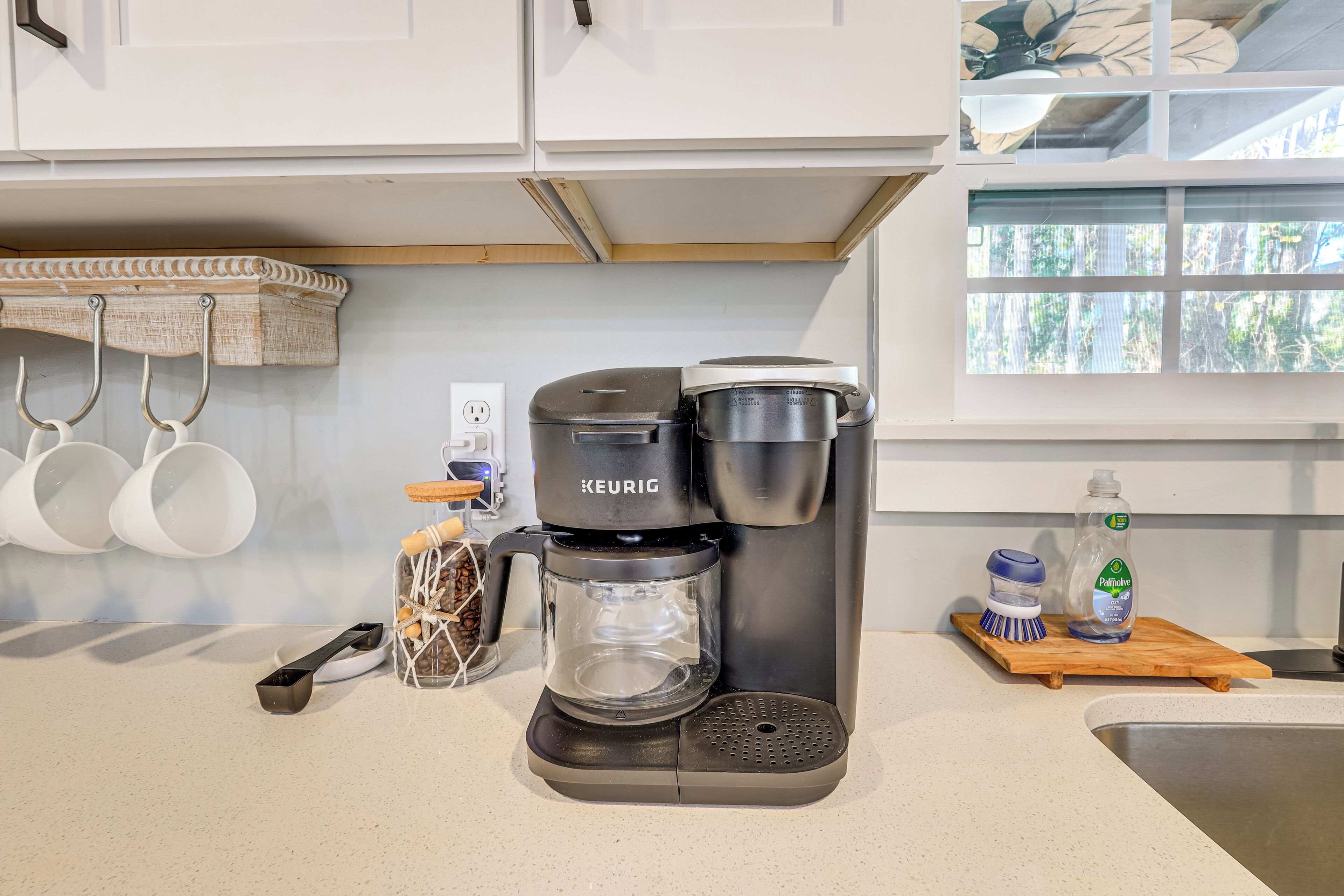 A modern kitchen with a Keurig coffee maker, a coffee grinder, and a bottle of dish soap on the counter.