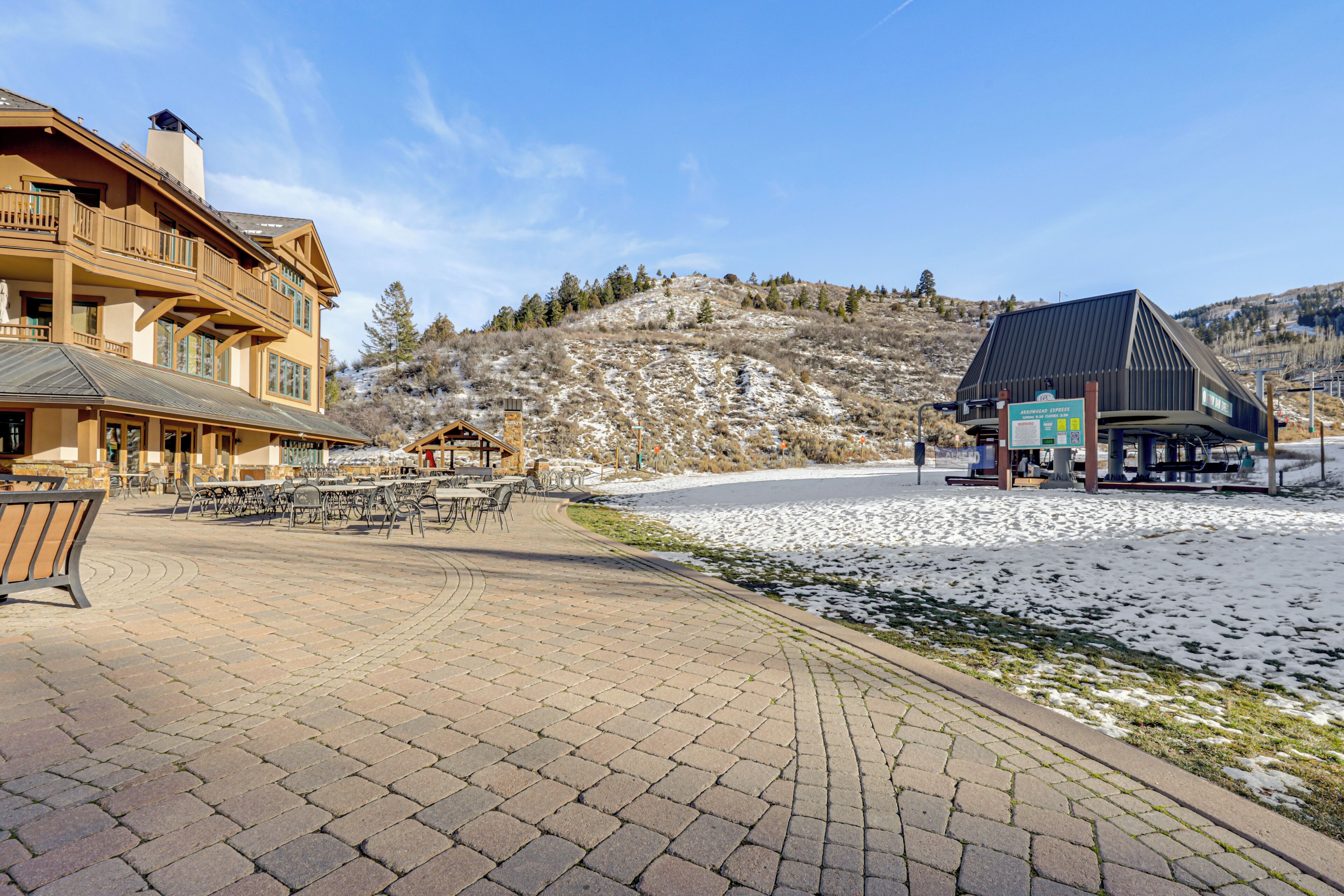 A hotel with a patio area, outdoor seating, and a view of a snowy landscape.