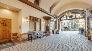 A spacious lobby with a wooden bench, stone walls, and a large arched doorway. - Ski-in/ski-out! Large Arrowhead Condo w/ Balcony (Edwards)