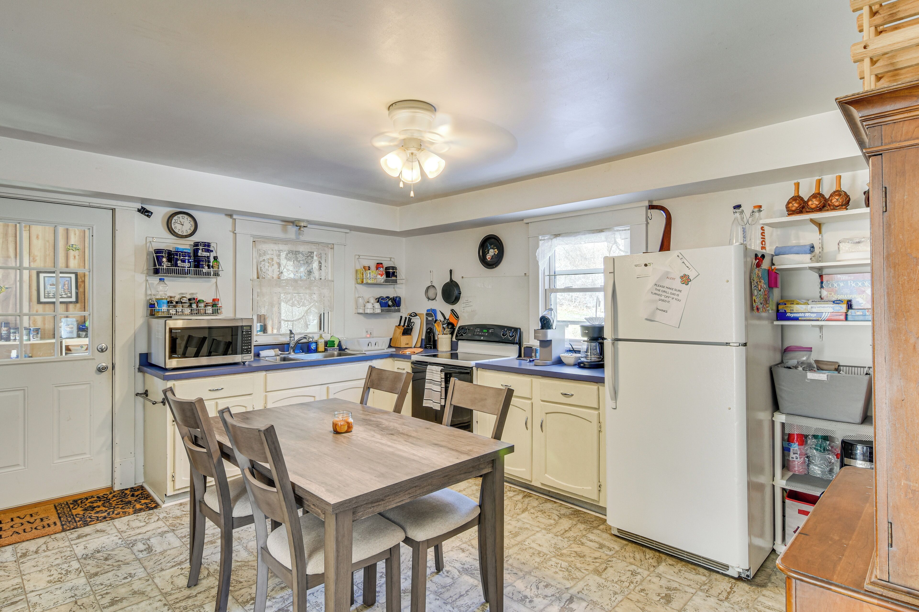 A kitchen with a dining table, chairs, a refrigerator, and various kitchen appliances.