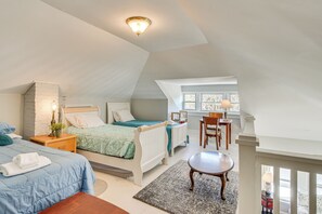 Une chambre à coucher comprenant un lit, une table de chevet, une lampe et donnant sur l’espace repas.