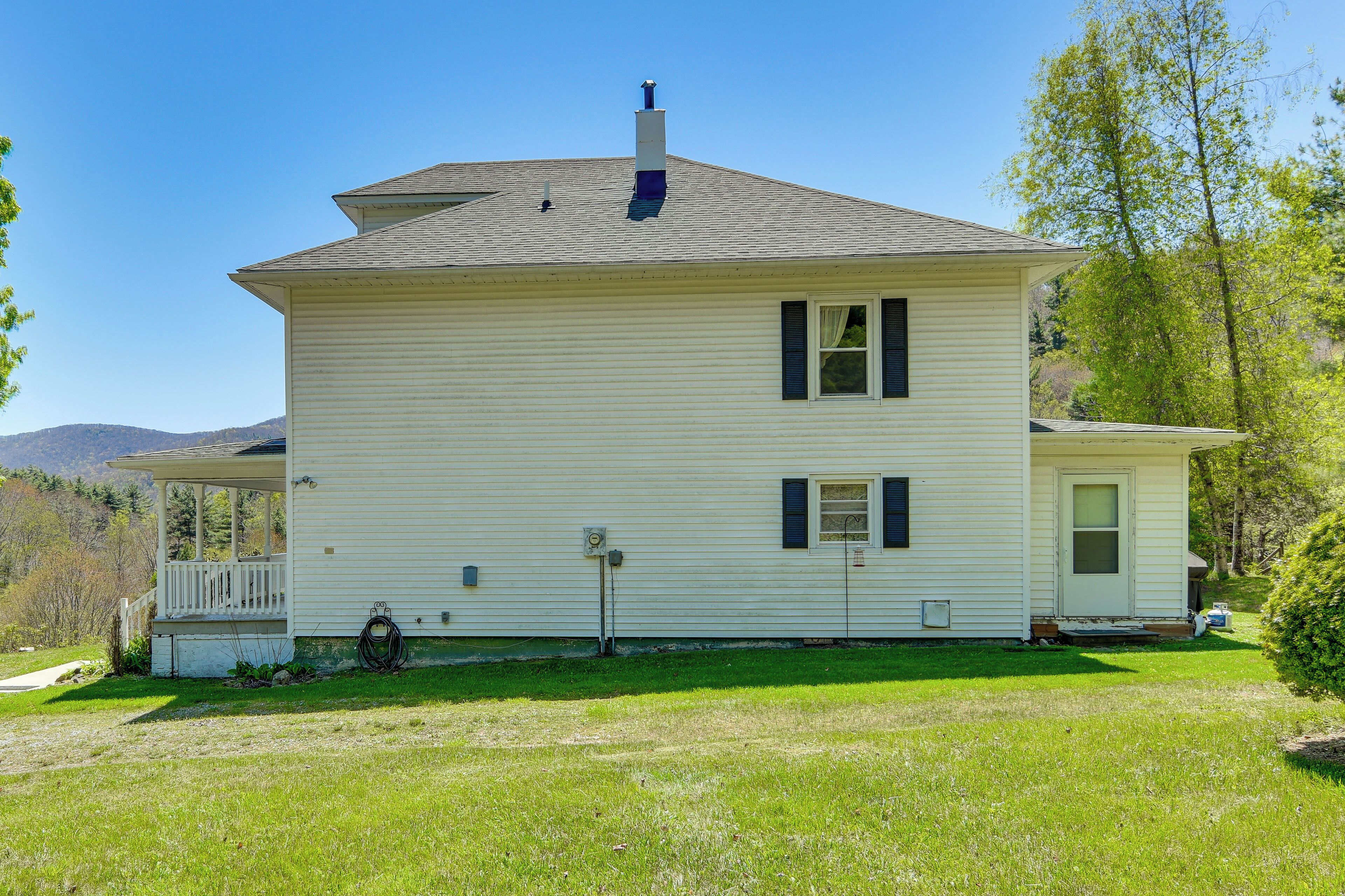 A two-story house with a porch, a chimney, and a small attached garage.