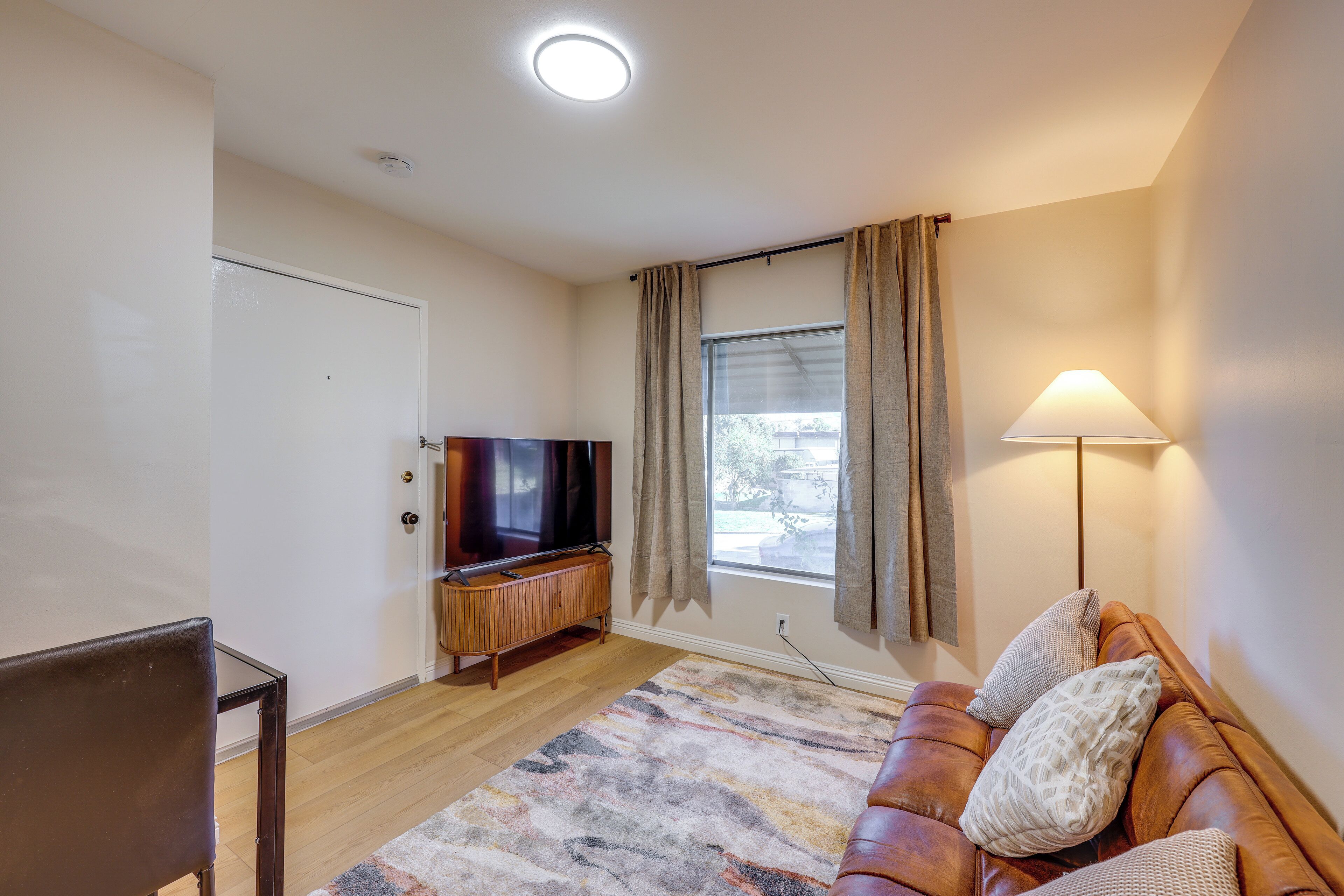 A living room with a leather sofa, a TV, and a lamp.