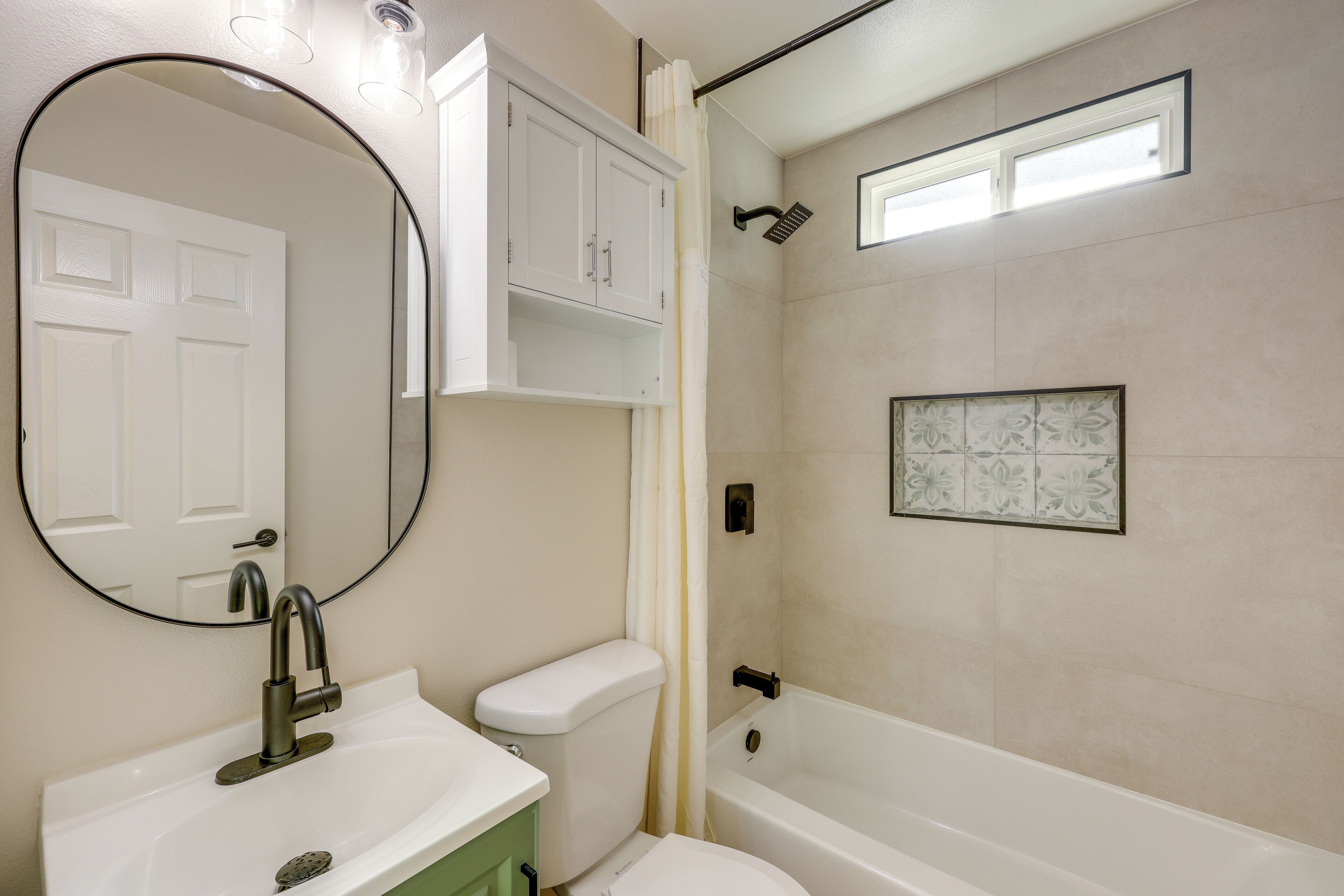 A bathroom with a white sink, a toilet, a bathtub, a showerhead, and a mirror.