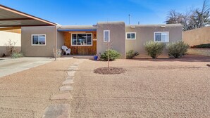Una casa moderna con un porche cubierto, un pequeño jardín y una puerta de madera.