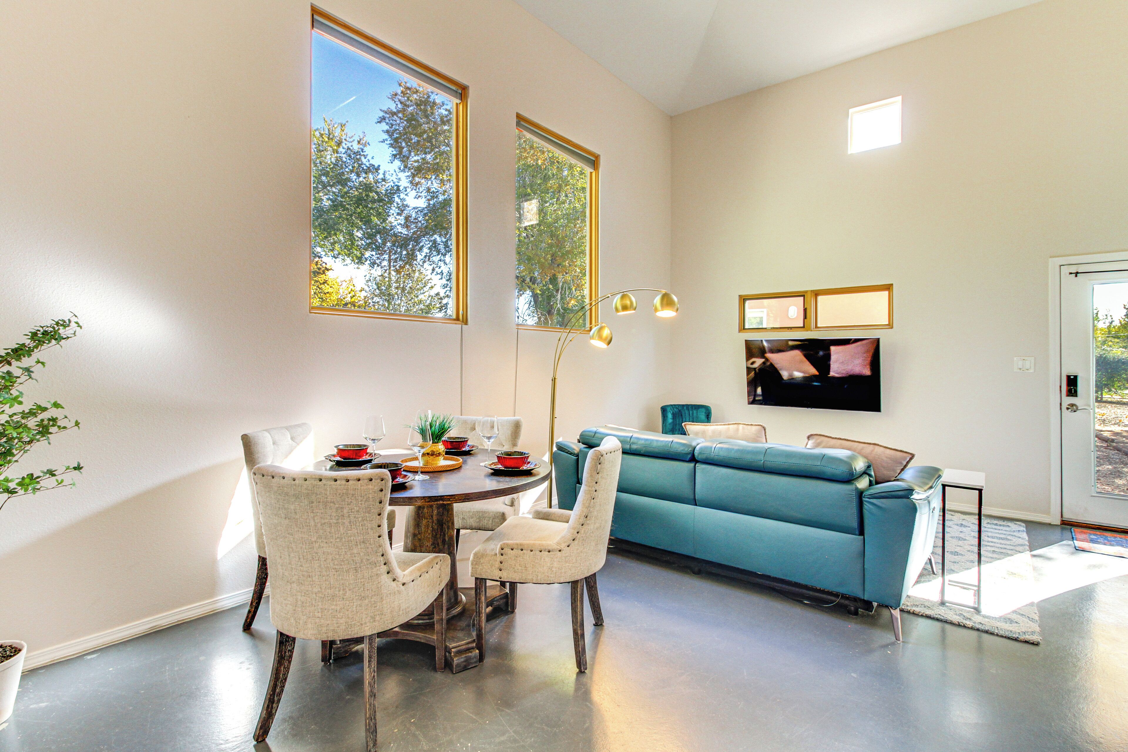 Ein modernes Wohnzimmer mit Essbereich, einem blaugrünen Sofa und einem flachbildfernseher an der Wand.