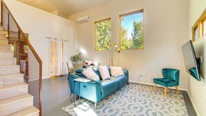 A modern living room with a blue sofa, a teal armchair, and a staircase with a wooden railing. - Stylish Home 2 Mi to Old Town Albuquerque! (Albuquerque)