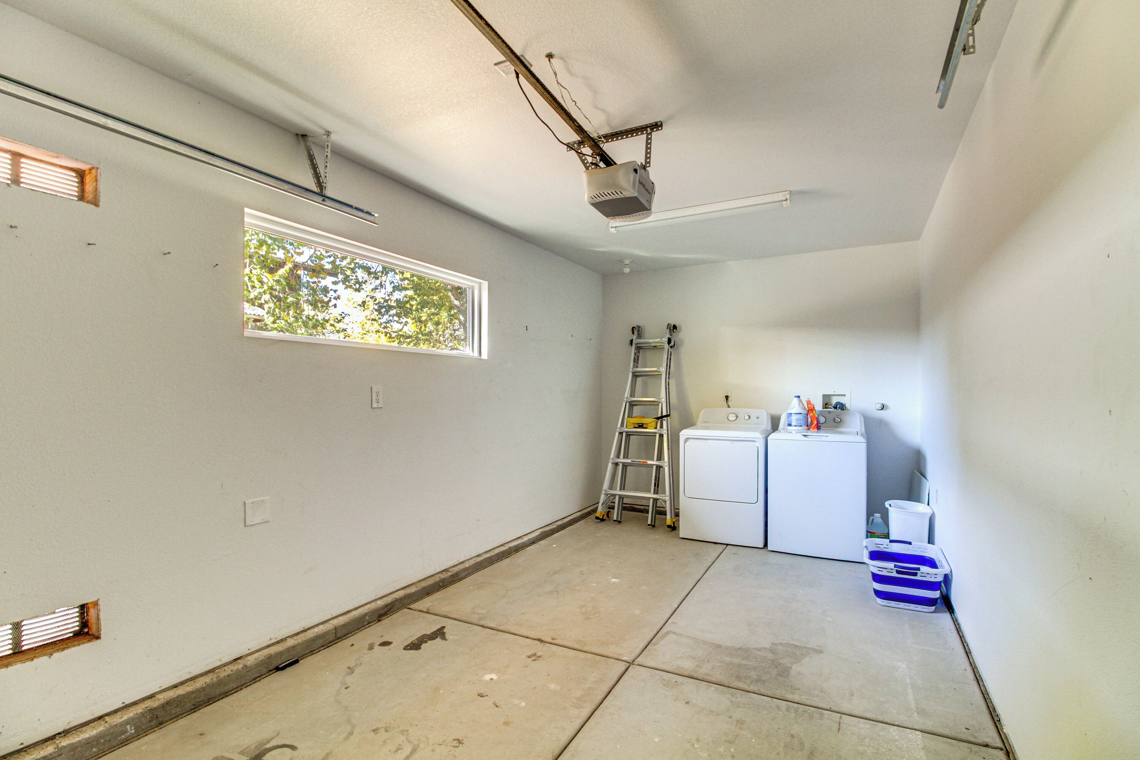 A room with a window, a ladder, a washing machine, and a projector on the ceiling.