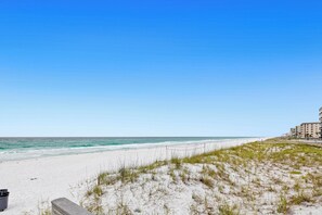 A beach with a clear sky, sandy shore, and a building in the background. - Beachfront Florida Penthouse w/ Pool Access! (Fort Walton Beach)