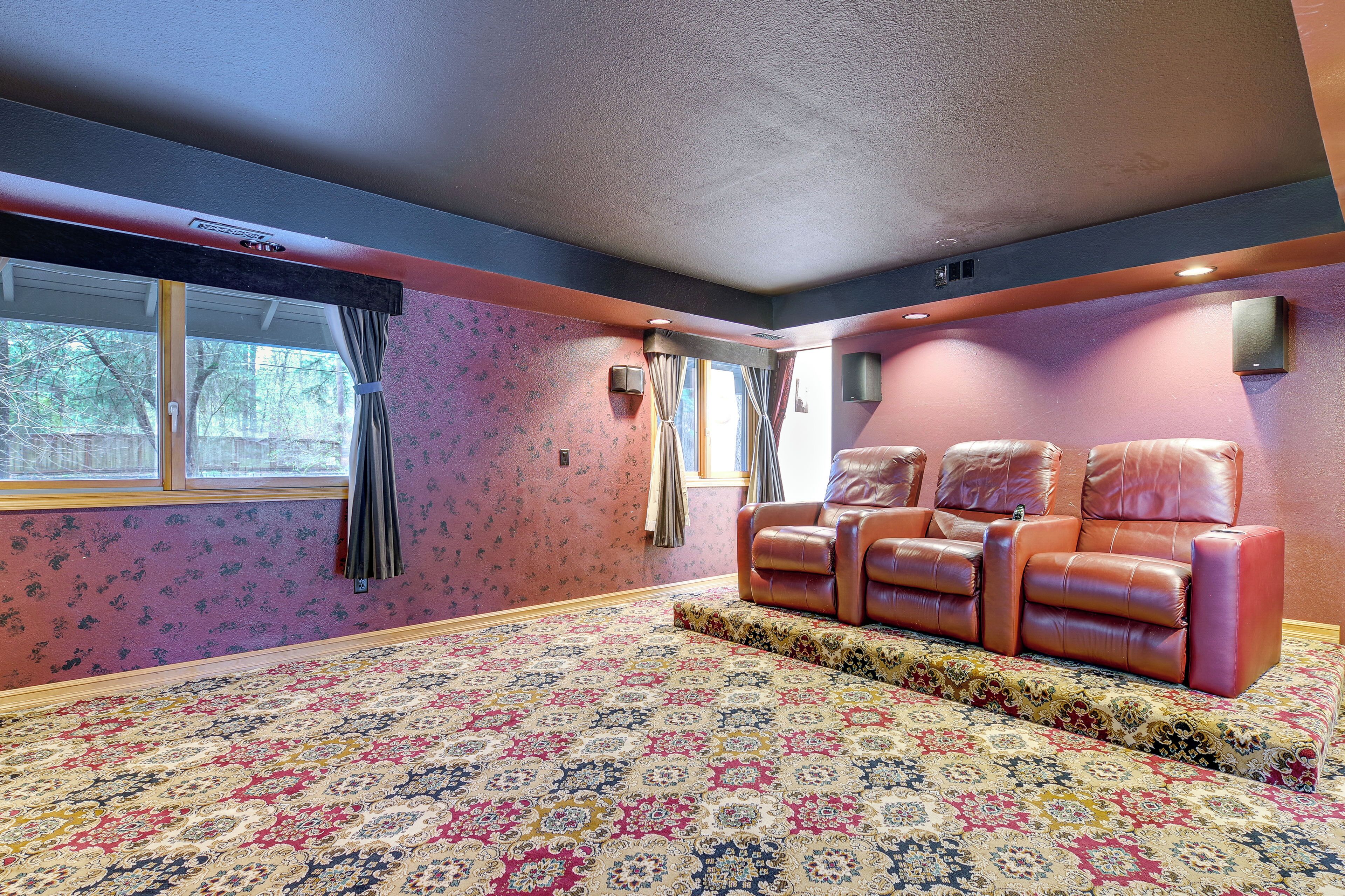 A room with a patterned carpet, a leather sofa, and a window with curtains.