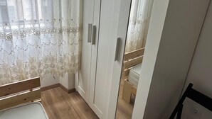 Makuuhuoneessa on suuri vaatekaappi, valkoisella patjalla varustettu sänky ja penkki.