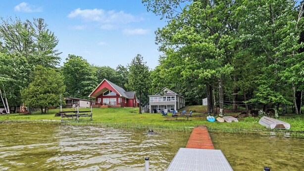A lakeside property with a dock, a red house, and a white building. - Newly Remodeled Lakeside Cottage. Sleeps 6! (Scottville)