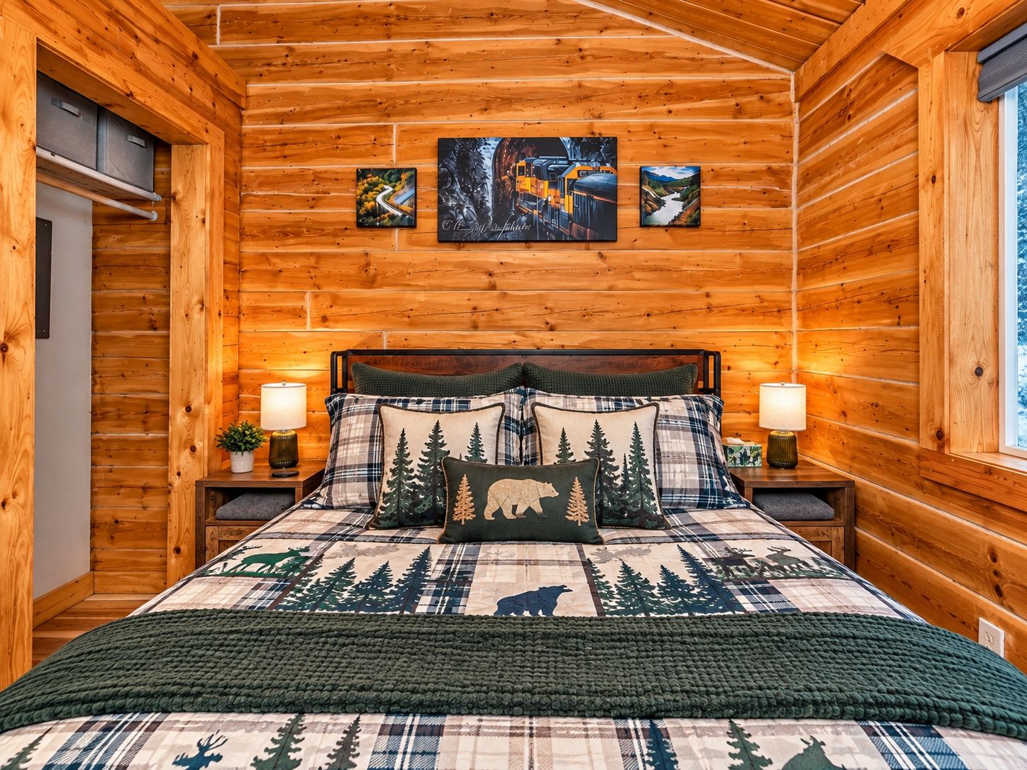 A wooden cabin bedroom with a bed, two bedside lamps, and three framed pictures on the wall.