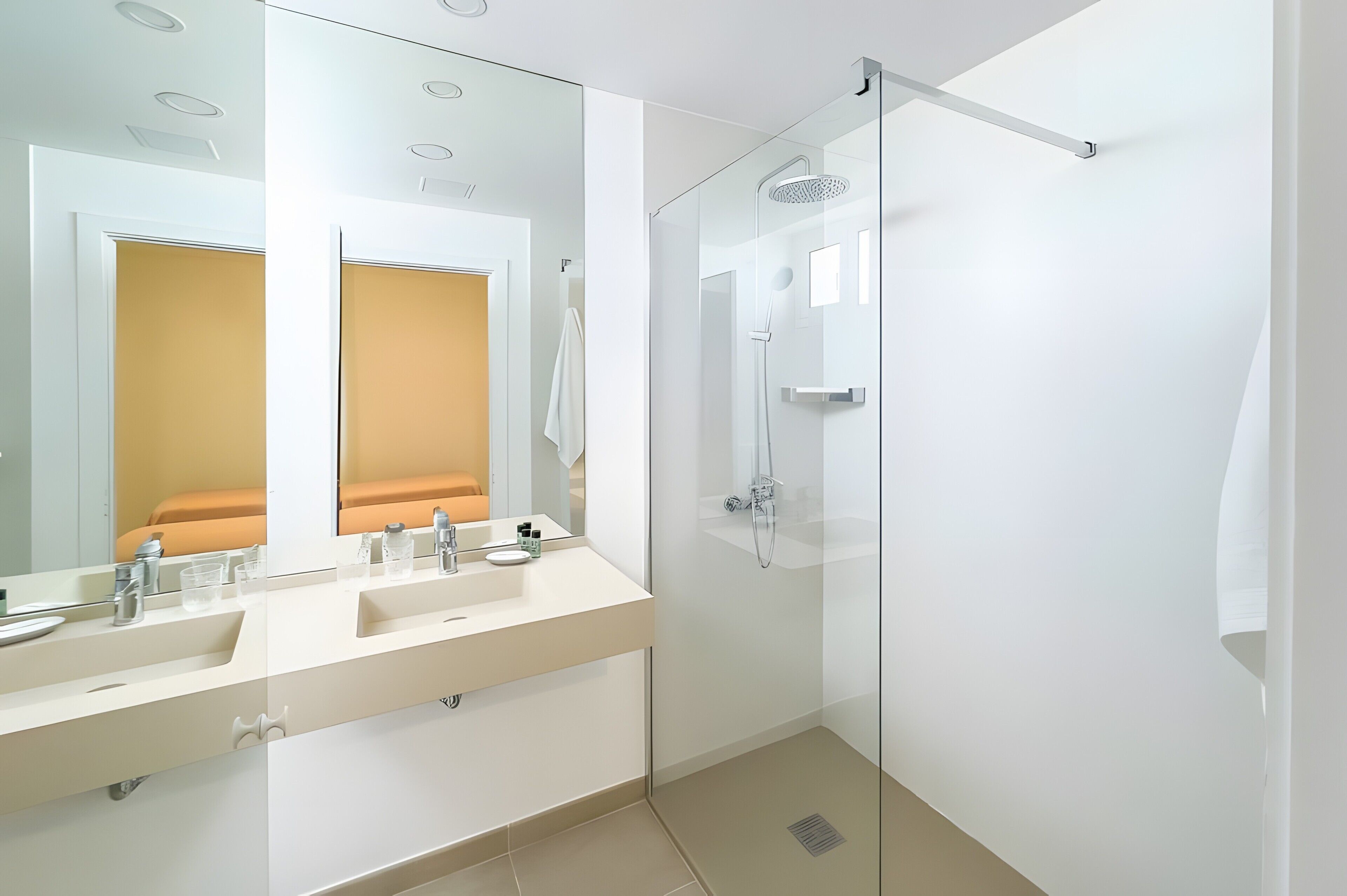 Une salle de bain moderne avec une douche à parois de verre, un meuble-lavabo à deux vasques et un grand miroir.