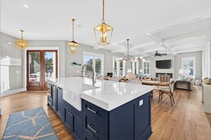 Cozinha moderna com uma ilha grande, luminárias pendentes e vista para o exterior.