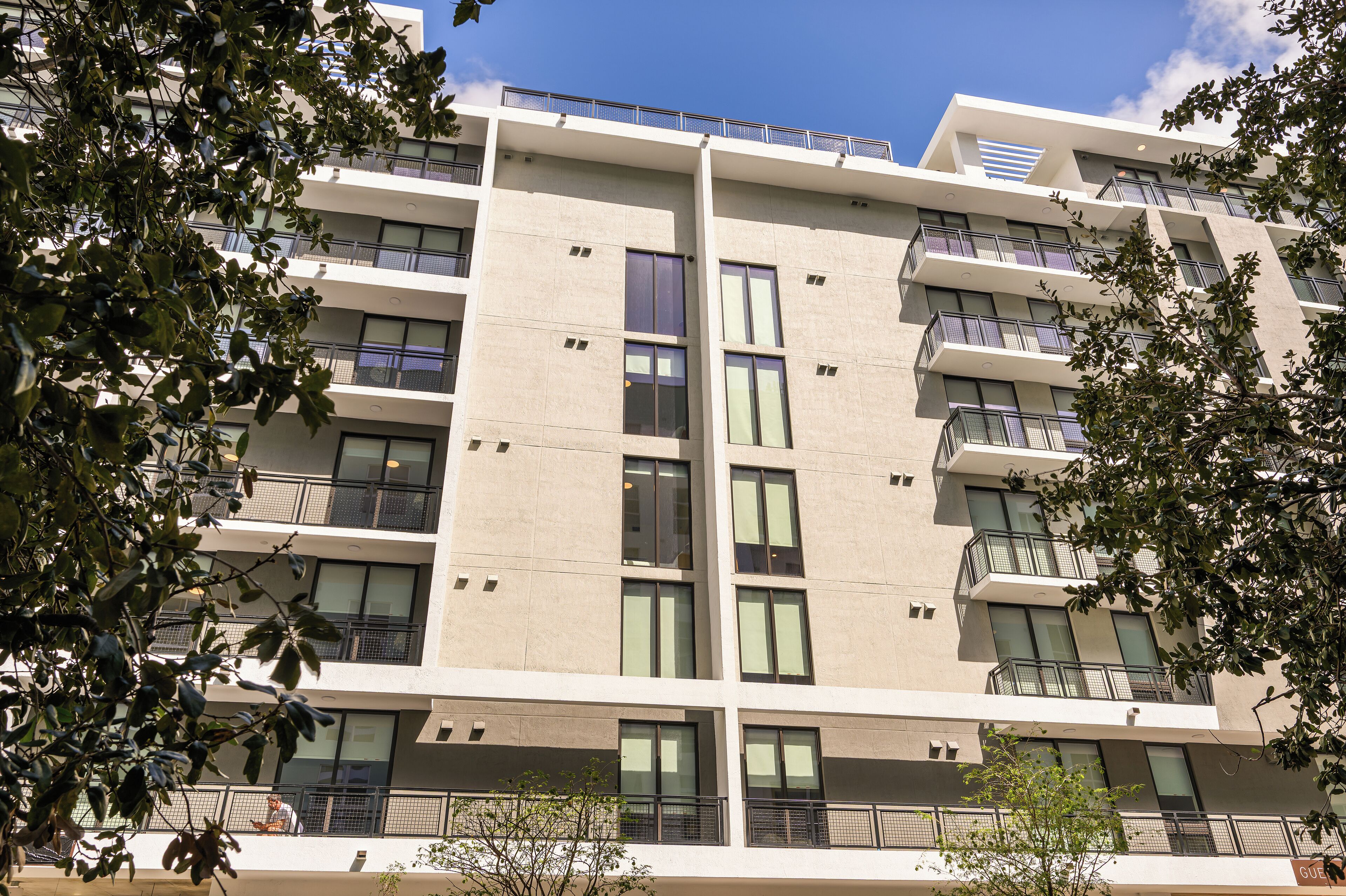 Un immeuble à plusieurs étages, doté de balcons, de grandes fenêtres et surplombant un ciel dégagé.