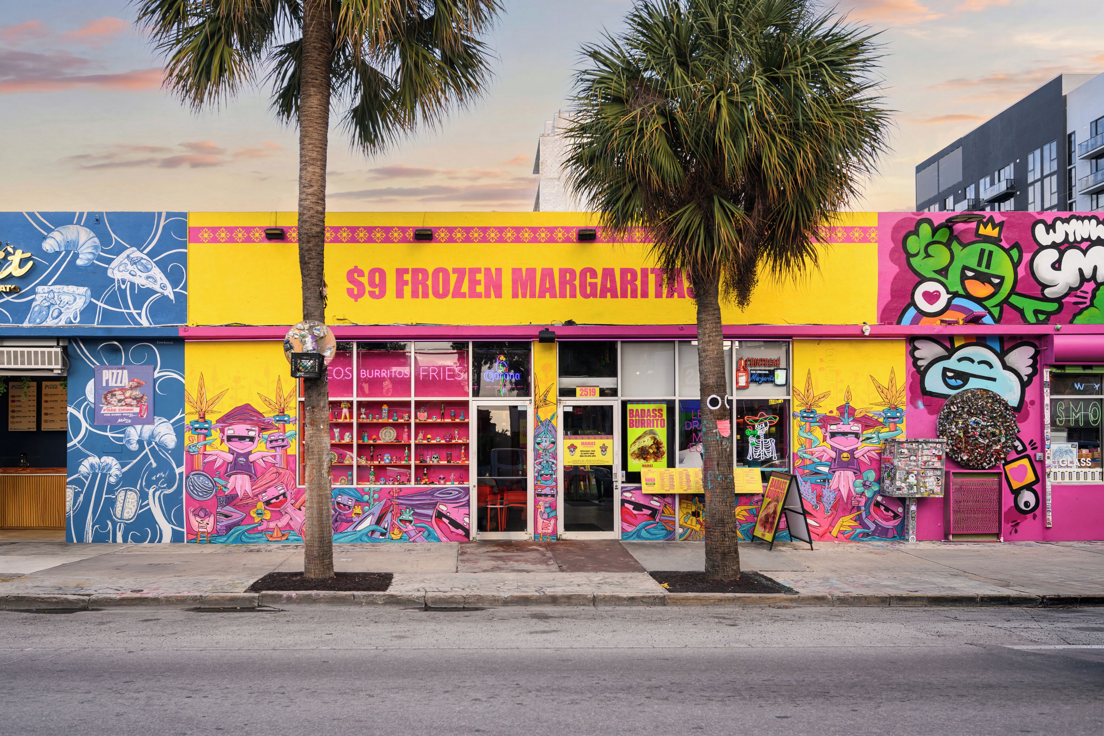 Une devanture de magasin aux couleurs vives, avec une enseigne indiquant « Margarita glacée à 9 $ » et une fresque murale.