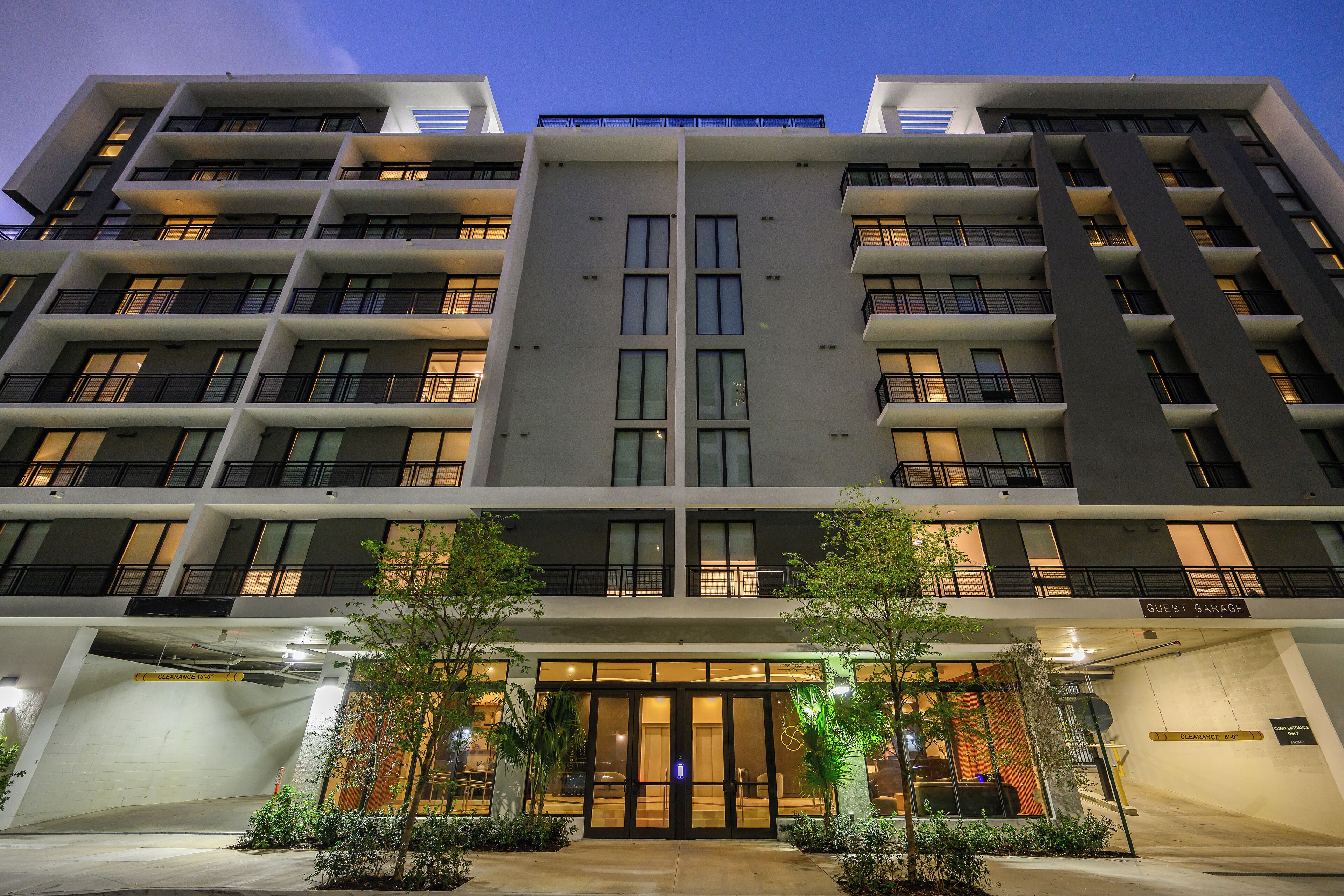 A multi-story hotel with a central entrance, balconies, and a guest garage.