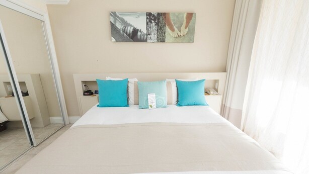 Une chambre d’hôtel avec un grand lit, deux tables de chevet, une commode, une lampe de chevet et une œuvre d’art accrochée au mur.