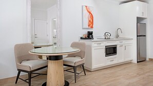 Une cuisine moderne avec des armoires blanches, un réfrigérateur en acier inoxydable, un four encastré et une machine à café posée sur le plan de travail.
