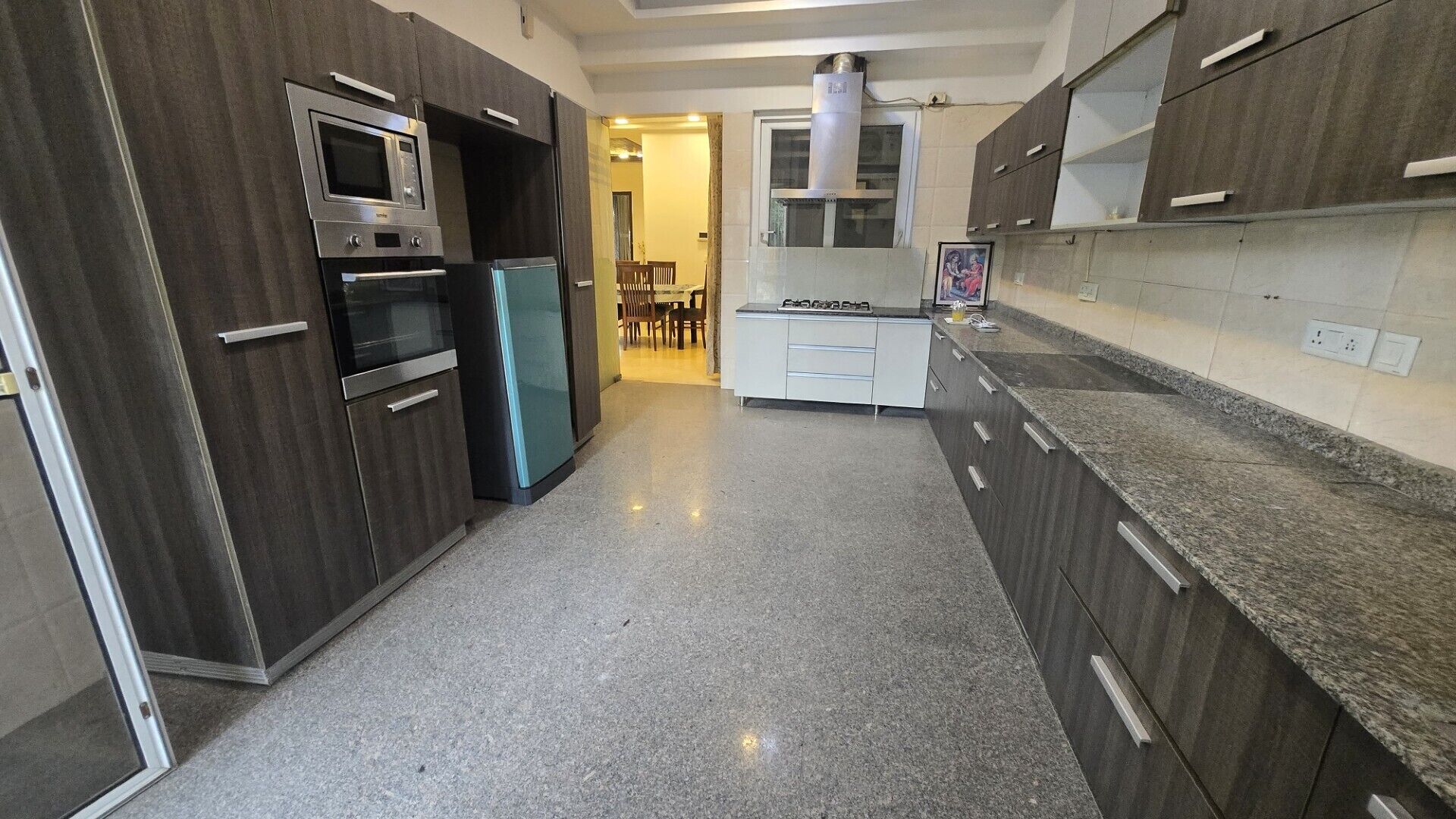 A modern kitchen with dark wood cabinets, stainless steel appliances, and a granite countertop.
