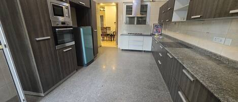 A modern kitchen with dark wood cabinets, stainless steel appliances, and a granite countertop.