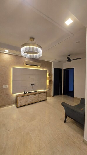 Un salon moderne doté d’un meuble de rangement intégré pour les appareils multimédias, d’un ventilateur de plafond et d’une grande fenêtre.