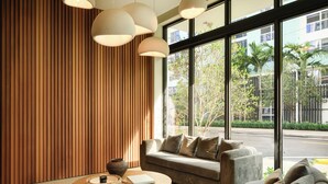 A modern interior with a sofa, a round wooden coffee table, and large windows offering a view of the street. - Edgewater 2BR w/ Balcony | Rooftop Pool + Gym | Sense28 by AvantStay (Miami)