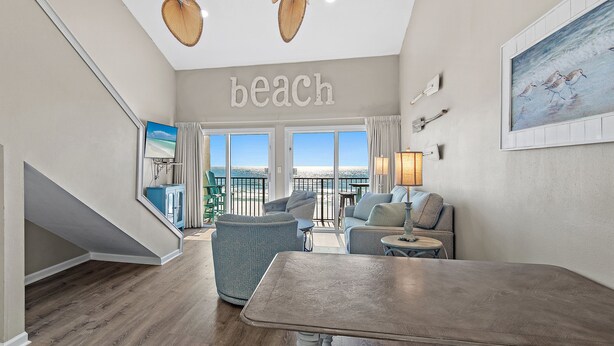 Een ruime woonkamer met uitzicht op het strand, een eettafel en comfortabele zitplaatsen.
