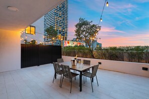 Une terrasse extérieure avec une table et des chaises, une bouteille de champagne et des guirlandes lumineuses.