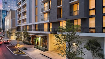 A multi-story hotel with balconies, a guest garage, and a well-lit entrance.